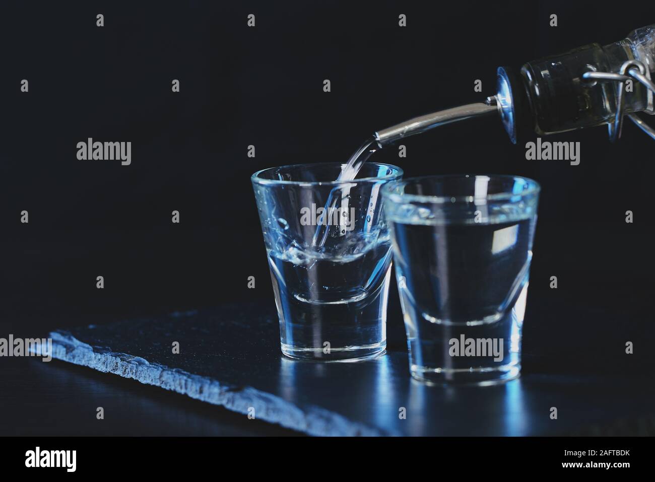 Flasche Wodka in ein Glas auf einem dunklen Hintergrund gegossen Stockfoto