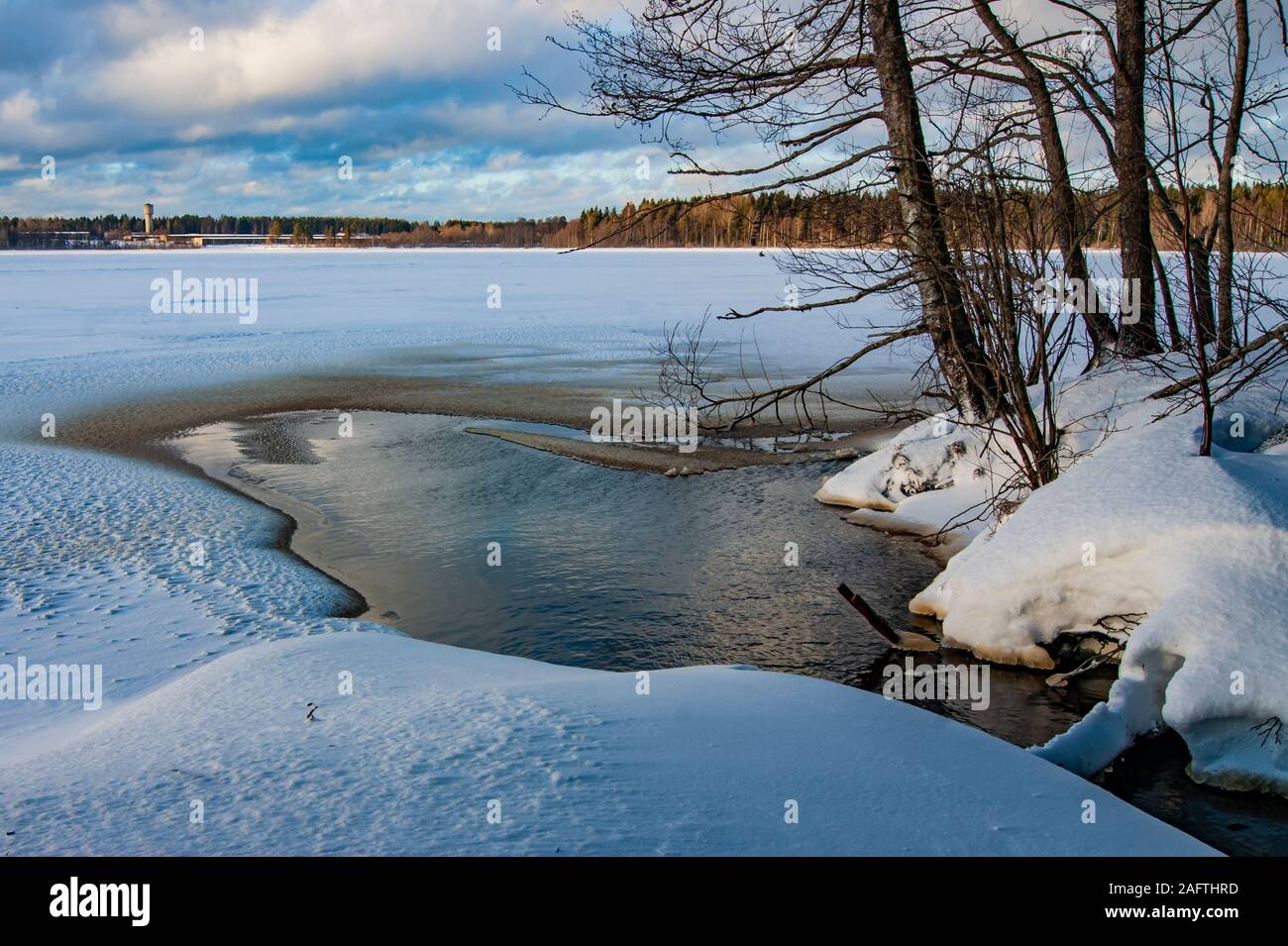 Wald bricht ein Pfad durch den Schnee und Eis. Der Fluss fließt in einen Winter Lake, aber das ist nicht, wo der Weg endet. Stockfoto