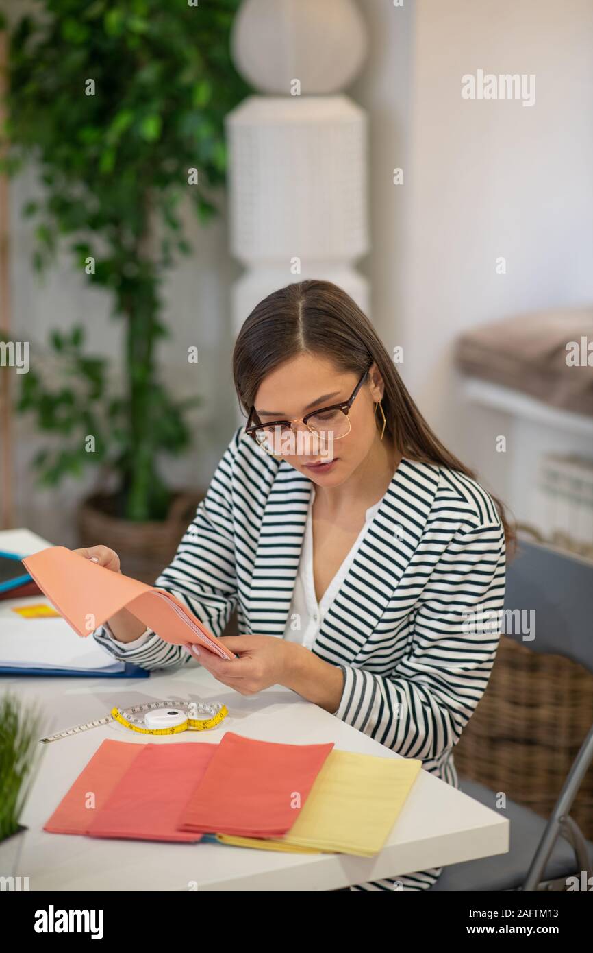 Schöne lange behaarte Frau Kontrolle der Materialien Stockfoto