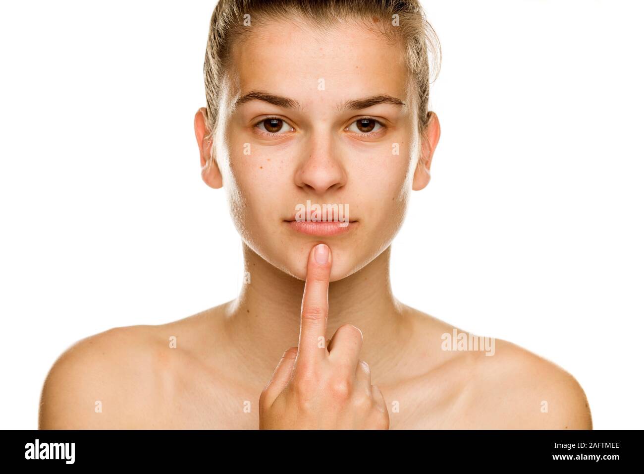 Eine Frau ohne Make-up berührt ihr Kinn auf weißem Hintergrund Stockfoto