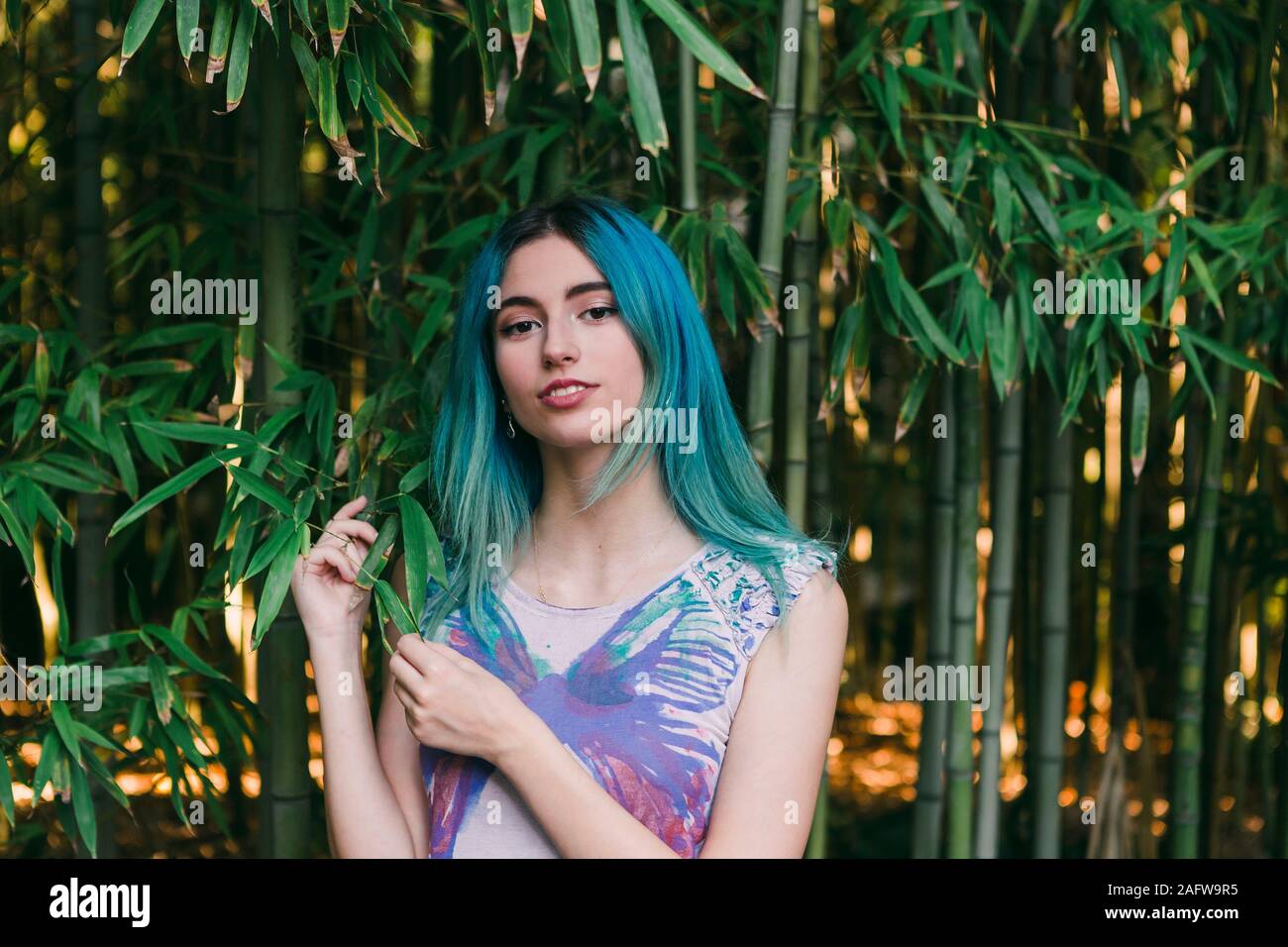 Portrait junge Frau mit blauen Haaren stehen unter Bambus Bäume Stockfoto