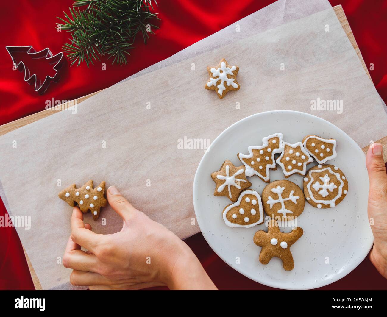 Hausgemachte cookies geformte Baum auf Platte und Hand Weihnachtsplätzchen in verschiedenen Formen: Stern, Tannenbaum, Weihnachten auf weißem Holz Hintergrund, flach Stockfoto