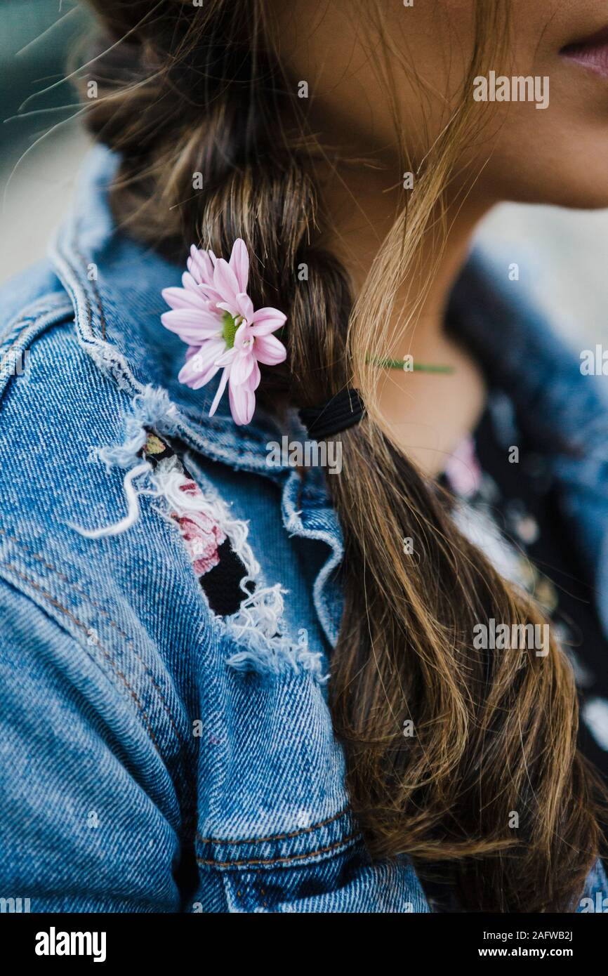 Close up junge Frau mit lila Blüte in geflochtenes Haar Stockfoto