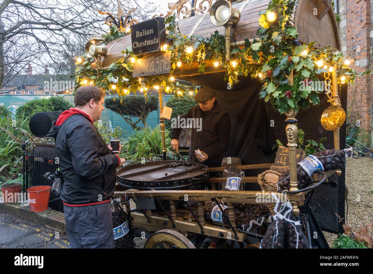 Kunden kaufen heiße Kastanien an der Winchester Weihnachtsmarkt neben der Kathedrale, Winchester, Hampshire, UK Stockfoto