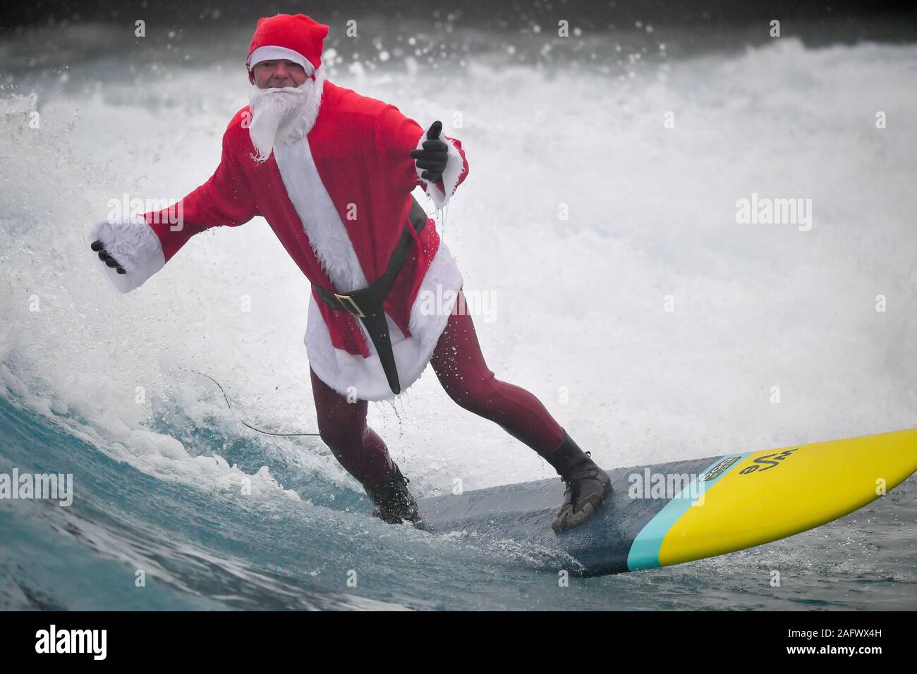 Ein Surfer in die festliche Stimmung als Santa gekleidet, wie er sich vorbereitet, die Wellen an das Landesinnere surfen Lagune an der Welle zu geben, in der Nähe von Bristol. Stockfoto