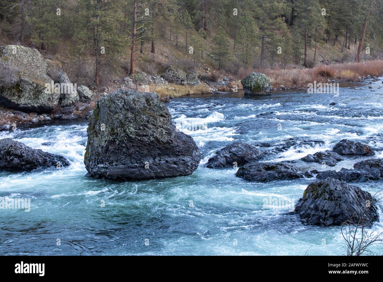 Wasser fließt in der Mitte von Felsen mit Bäumen Im Hintergrund Stockfoto