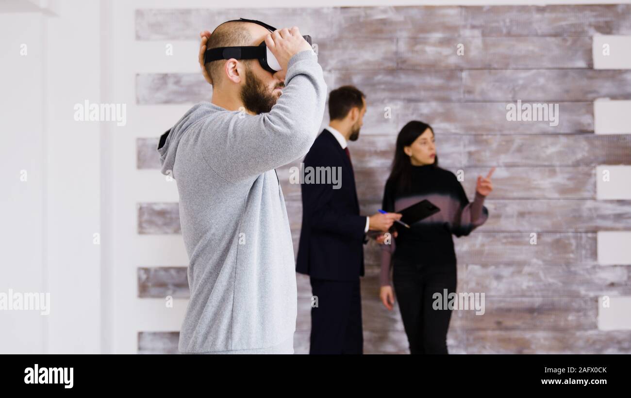 Erleben virtuelle Realität mit Headset in die neue Wohnung und Frau im Gespräch mit real estate agent im Hintergrund. Stockfoto