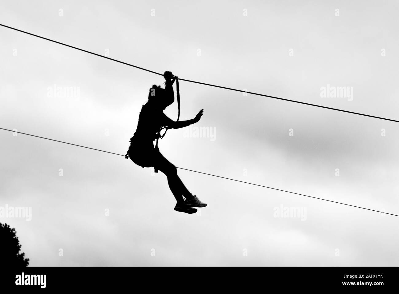 Graustufenaufnahme einer Person in einem Seilrutschenrennen Unter dem klaren Himmel Stockfoto