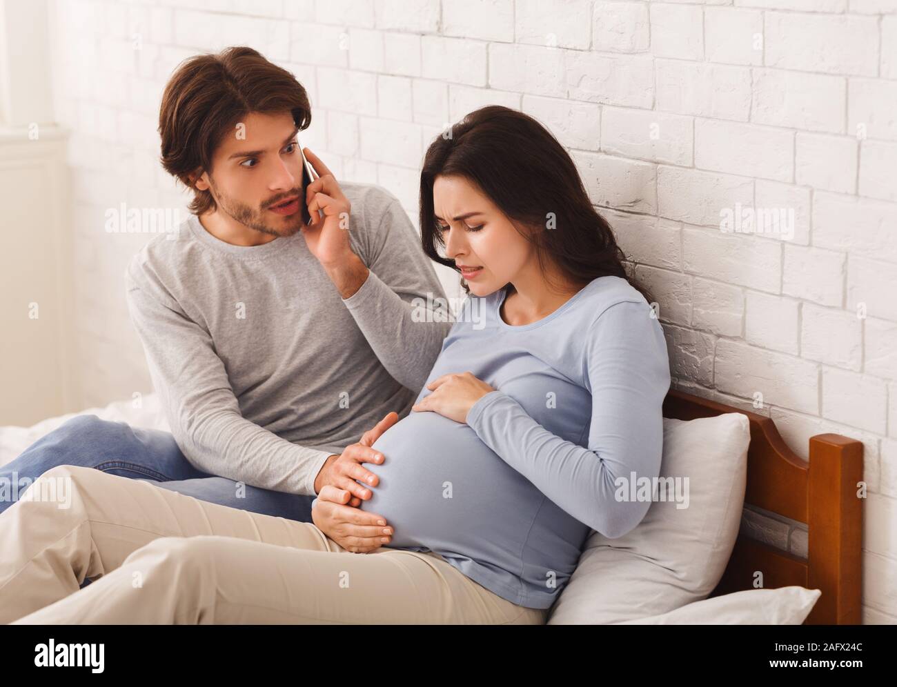 Besorgt, Mann, Doktor für seine schwangere Frau in Wehen Stockfoto