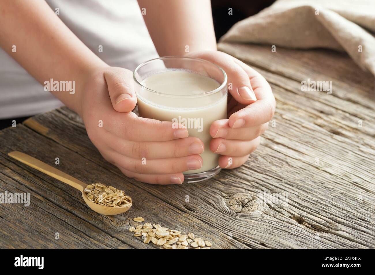 Junge Erwachsene Händen hält Glas hausgemachten organische Hafermilch. Das gesunde Essen laktosefreie Milch Ersatz Konzept. Close up, selektive konzentrieren. Stockfoto