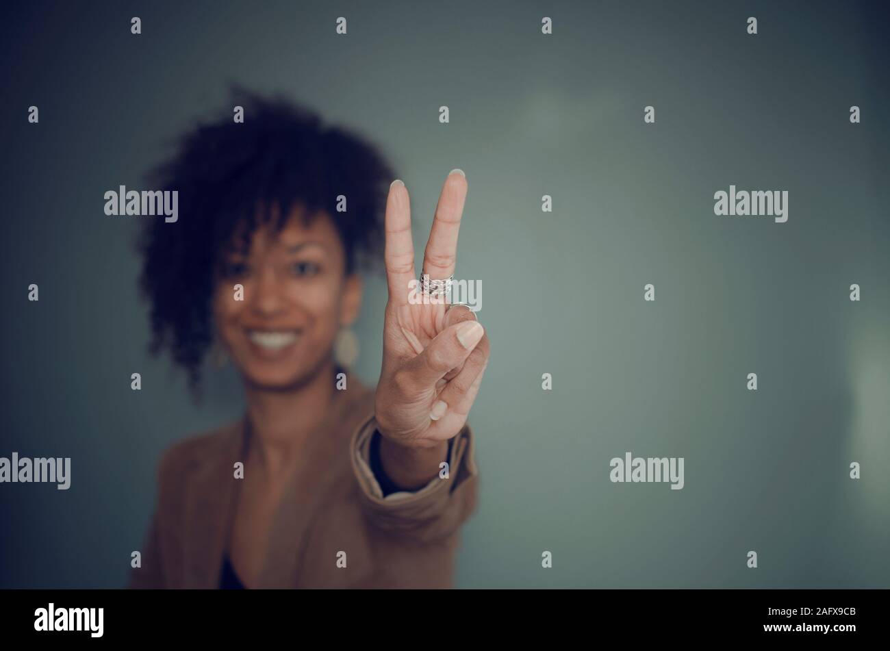 Selektive Fokussierung auf die Hand (mit Ringen) einer schwarzen Frau, die zwei Finger als Siegesgeste zeigt Stockfoto