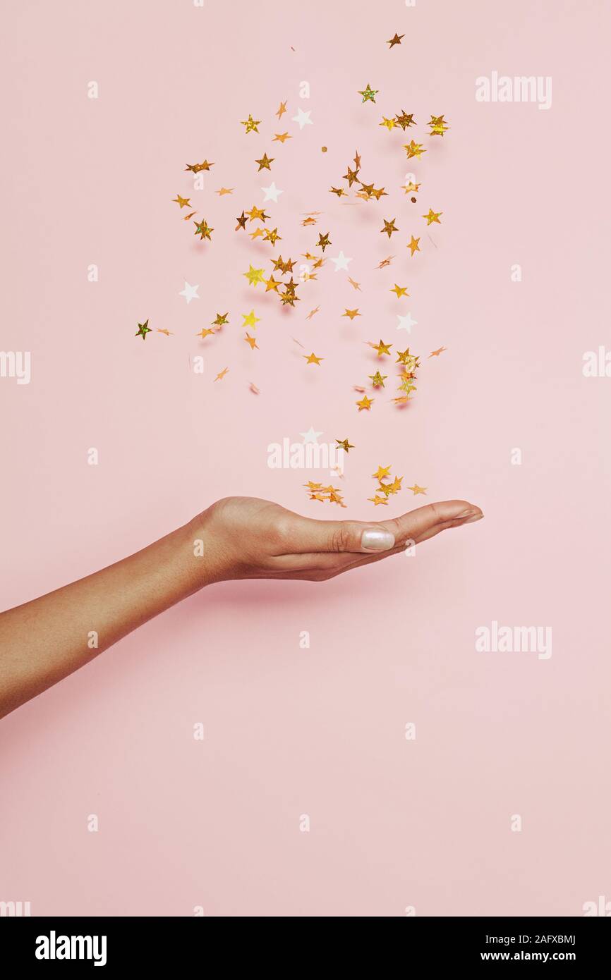 Blasen Konfetti Sterne Einrichtung in Frau hand auf rosa Hintergrund. Urlaub, Fantasie und Vorstellungskraft Konzept Stockfoto