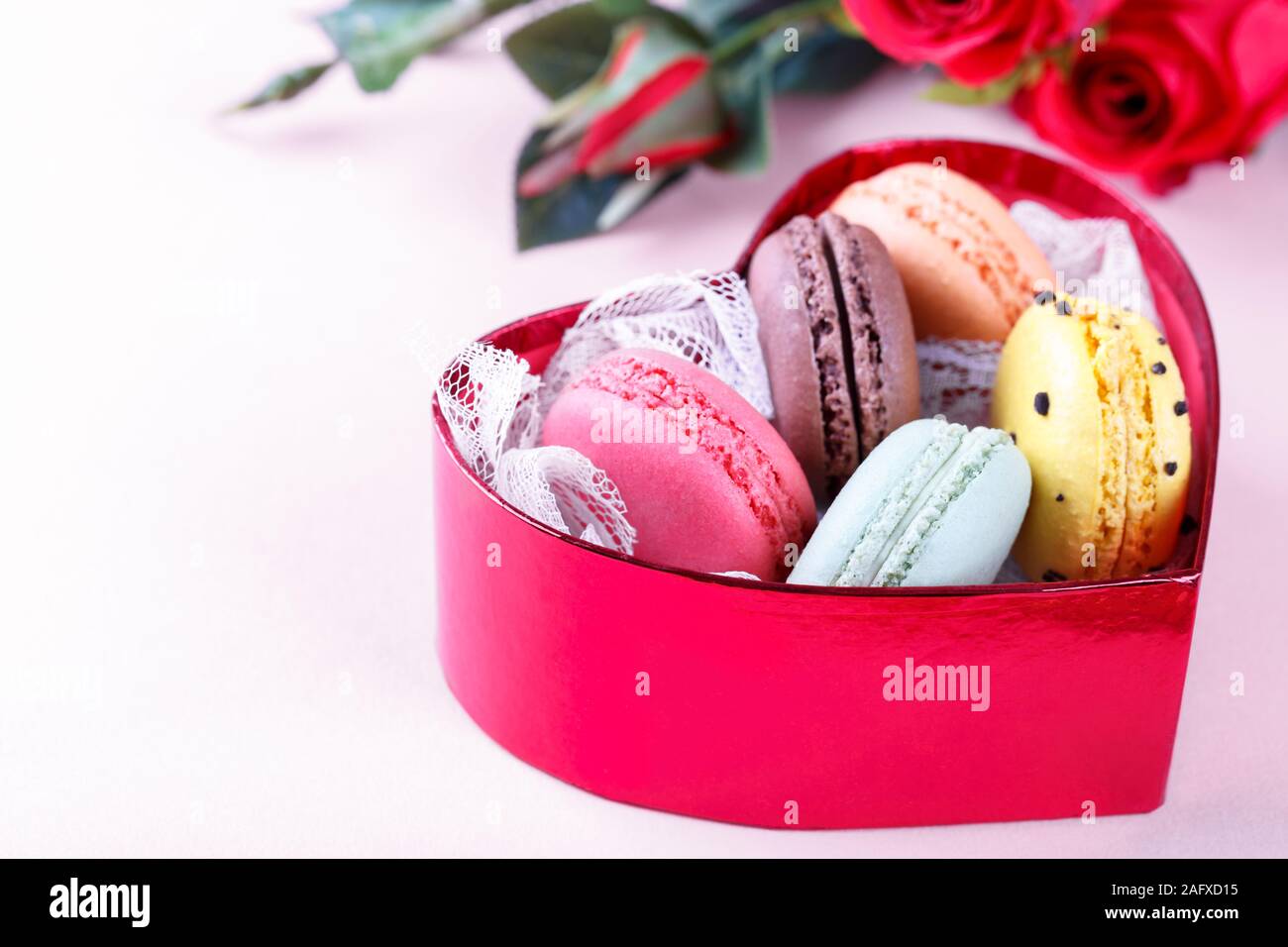 Bunte französische Macarons in einem Herzförmigen Geschenkbox auf rosa Hintergrund traditioanal Dessert in Frankreich, Valentinstag Konzept Stockfoto
