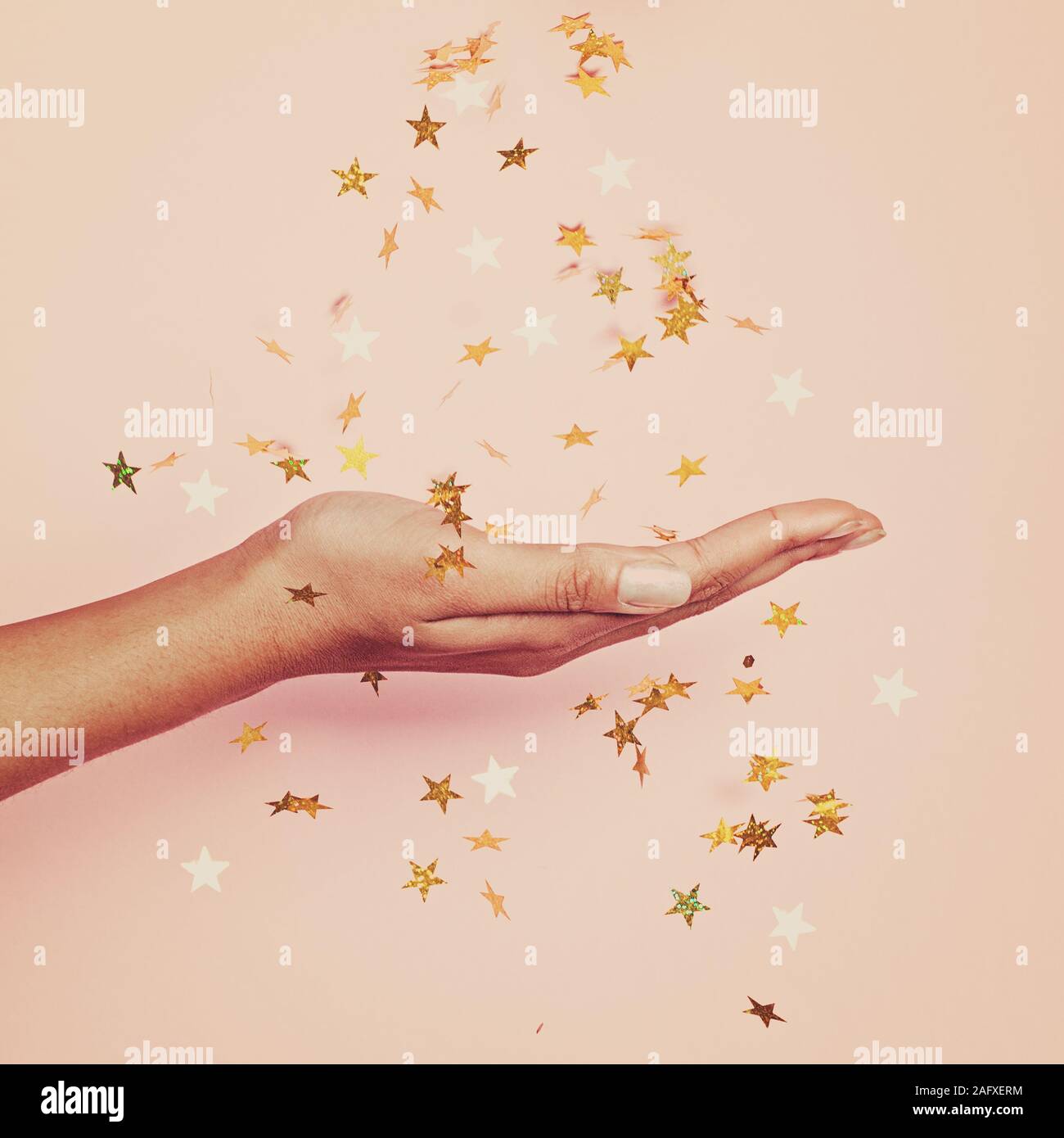 Magische gold Konfetti Sterne Dekoration in weiblicher Hand auf Pastell rosa Hintergrund Stockfoto