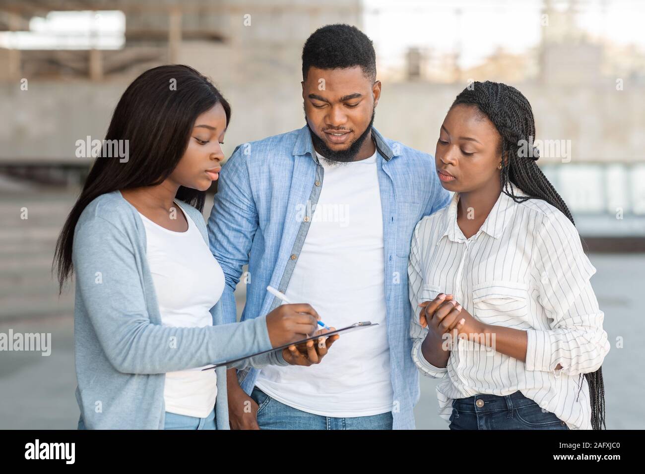 Schwarze weibliche Interviewer Durchführung der Umfrage mit jungen afrikanischen amerikanischen Paar im Freien Stockfoto