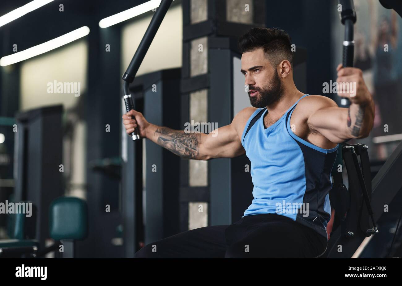 Sportlicher Kerl Ausübung auf Trainingsgeräten im Fitnessstudio Stockfoto