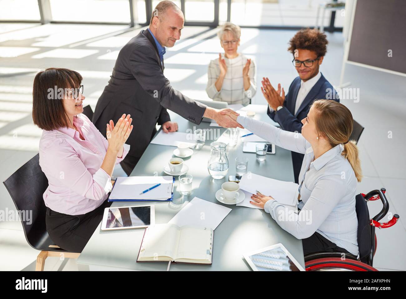 Geschäftsmann mit Handshake zu Business Frau im Rollstuhl in einer Besprechung Stockfoto