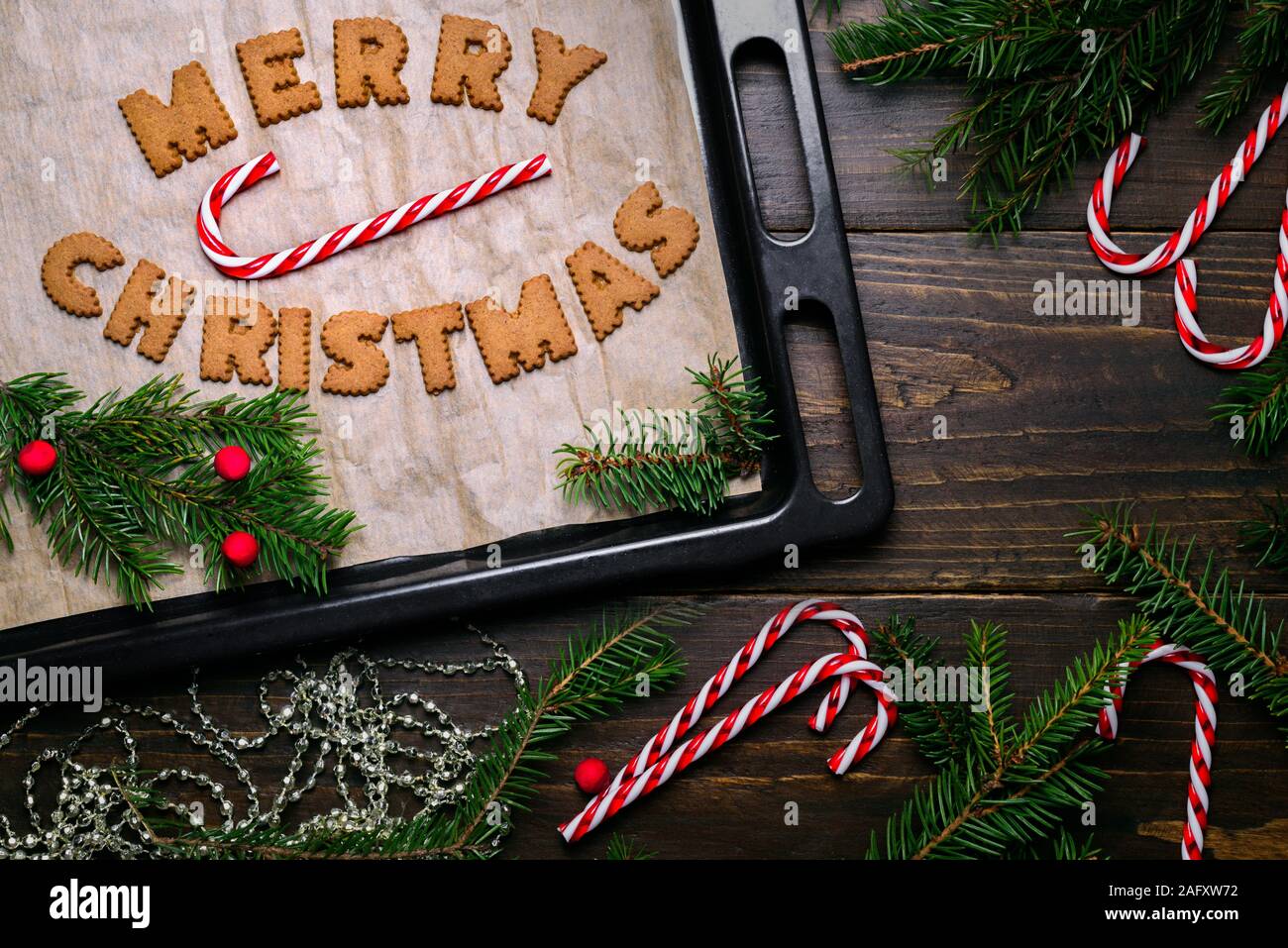 Wörter Frohe Weihnachten aus Cookies auf backblech Holztisch und Dekorationen Stockfoto