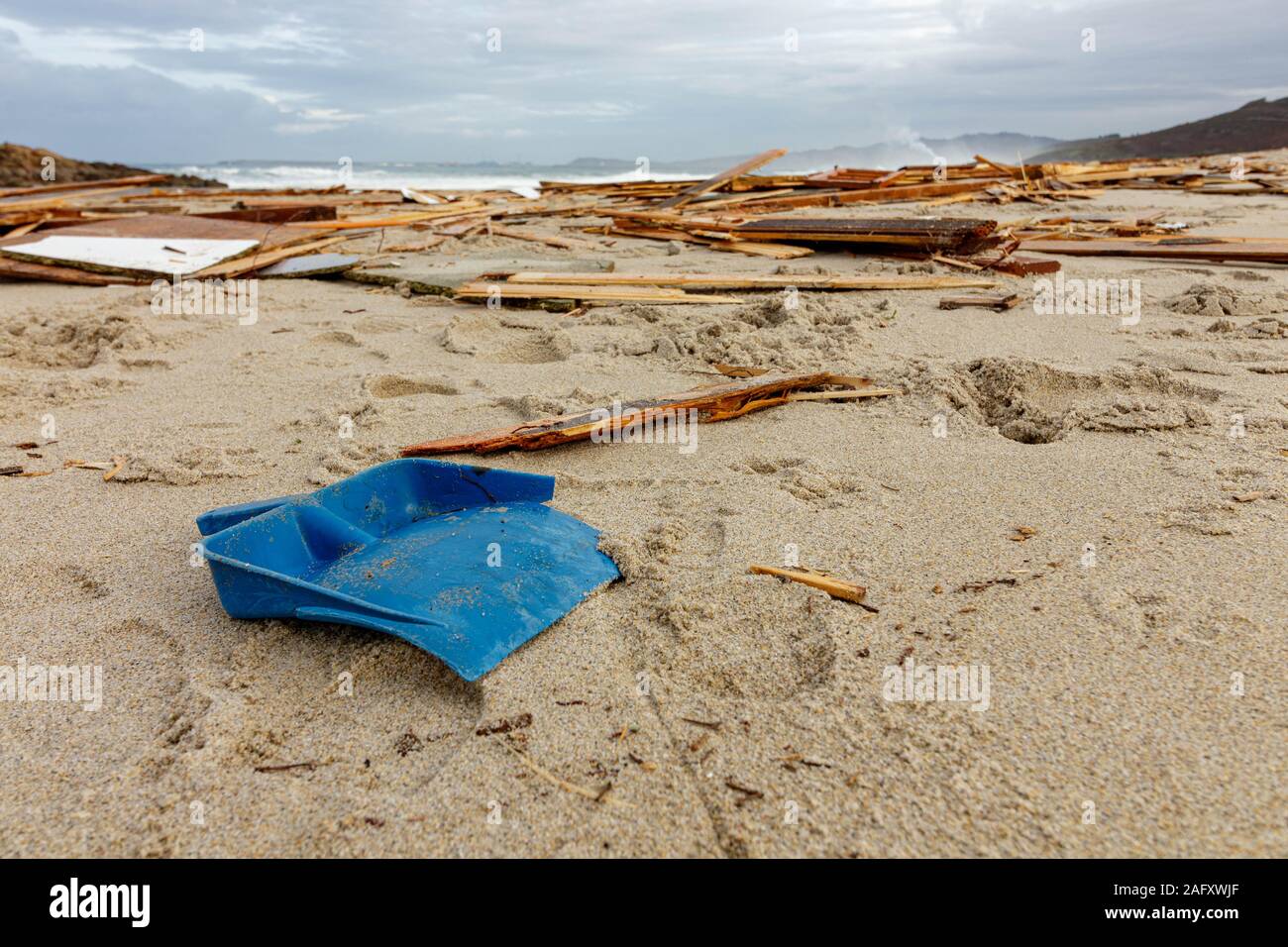 Barranan/Spanien - 15. Dezember 2019: Kunststoff blau Schaufel an einem Strand mit der zerschmetterten Reste eines hölzernen Beach Hut Stockfoto