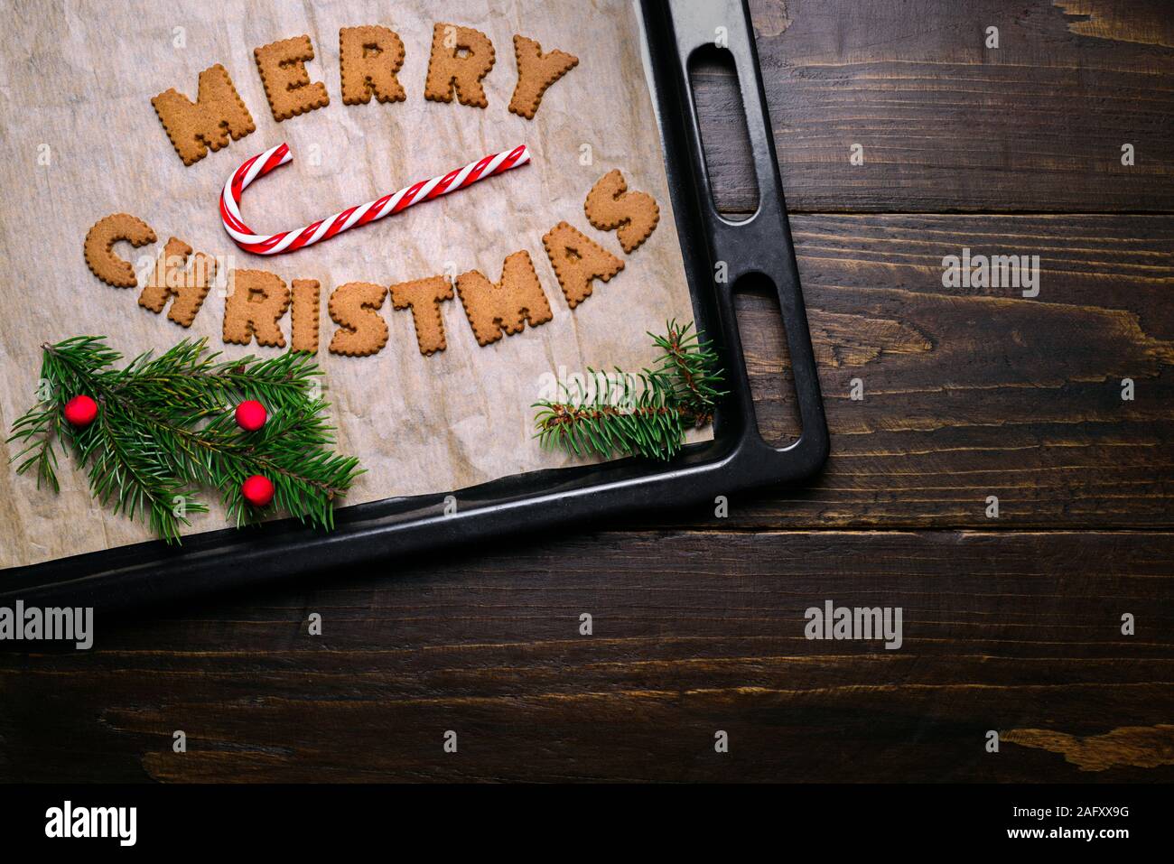 Wörter Frohe Weihnachten aus Cookies auf backblech Holztisch und Dekorationen Stockfoto