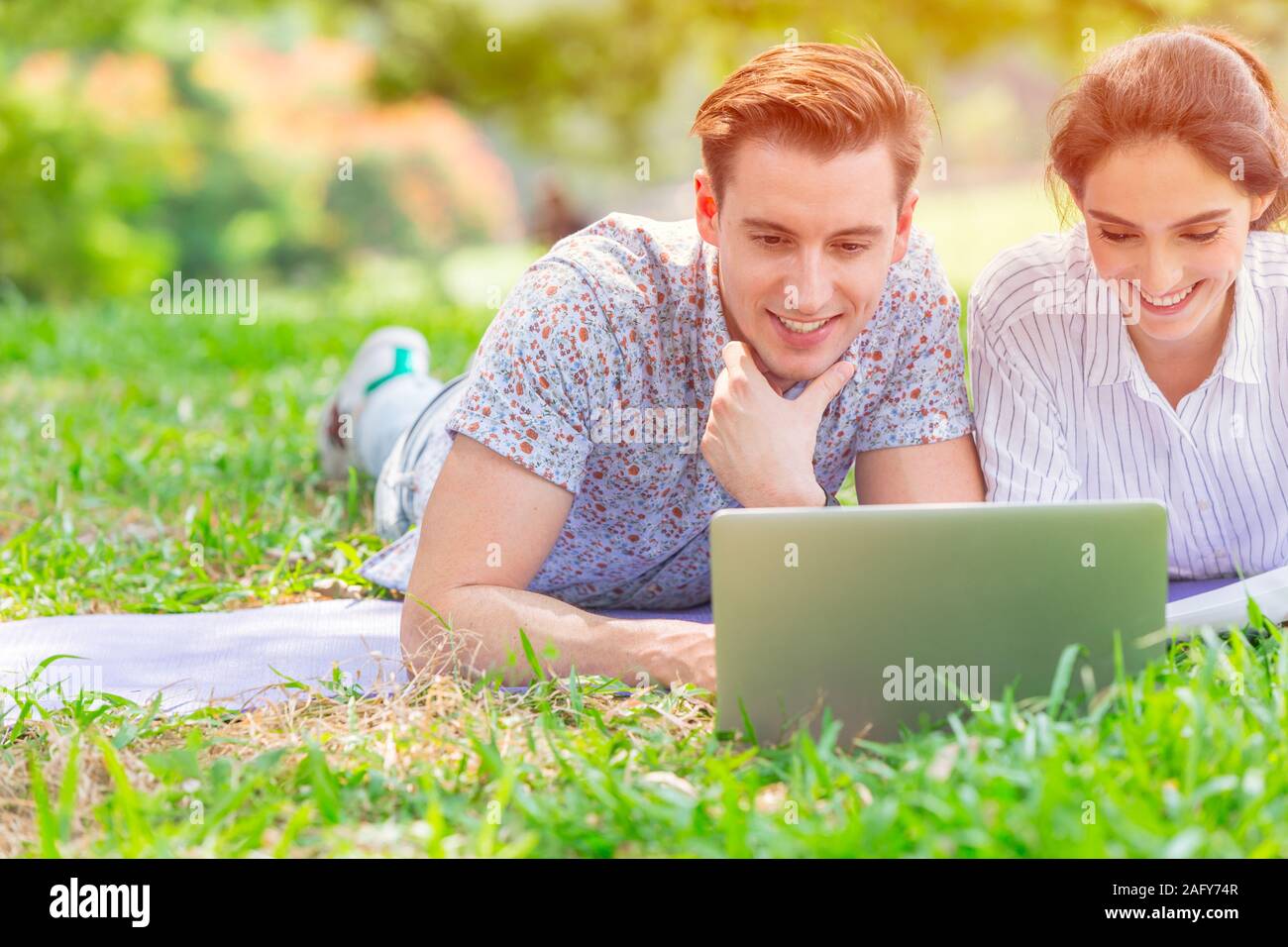 Paar business Liebhaber zusammen mit at laptop Bildschirm glücklich an und lächeln outdoor Green Park. Stockfoto