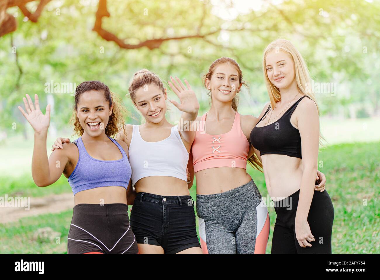 Gruppe von gesunden Sport Frauen Freund zusammen Hi 5 Hand Gruß suchen Kamera outdoor Green Park für Sitzung Training zusammen. Stockfoto