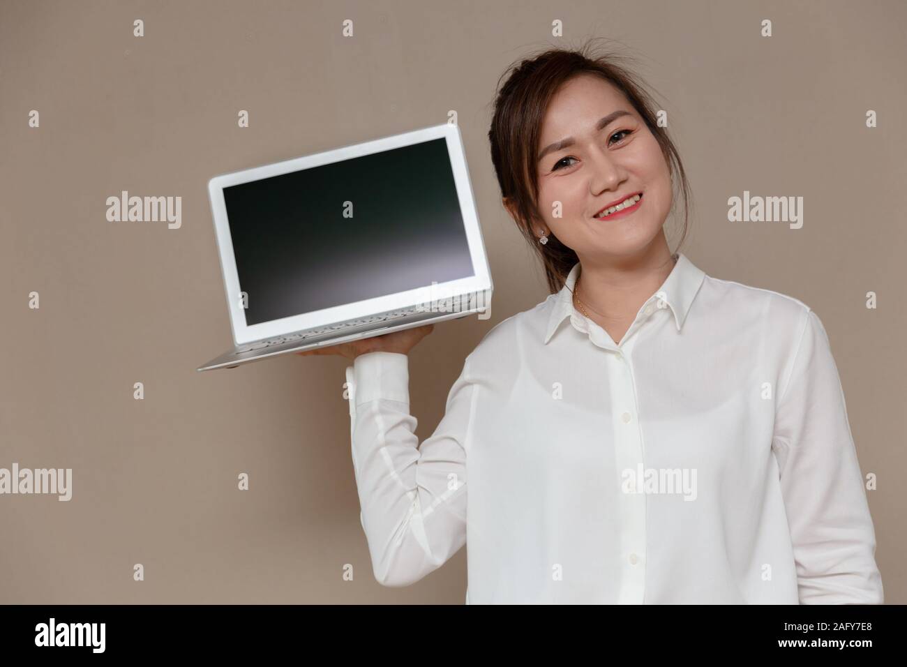 Asiatische Frau lächelnd einzigen Griff computer Laptop für die neuen dünnen und leichten Laptop Computer. Stockfoto