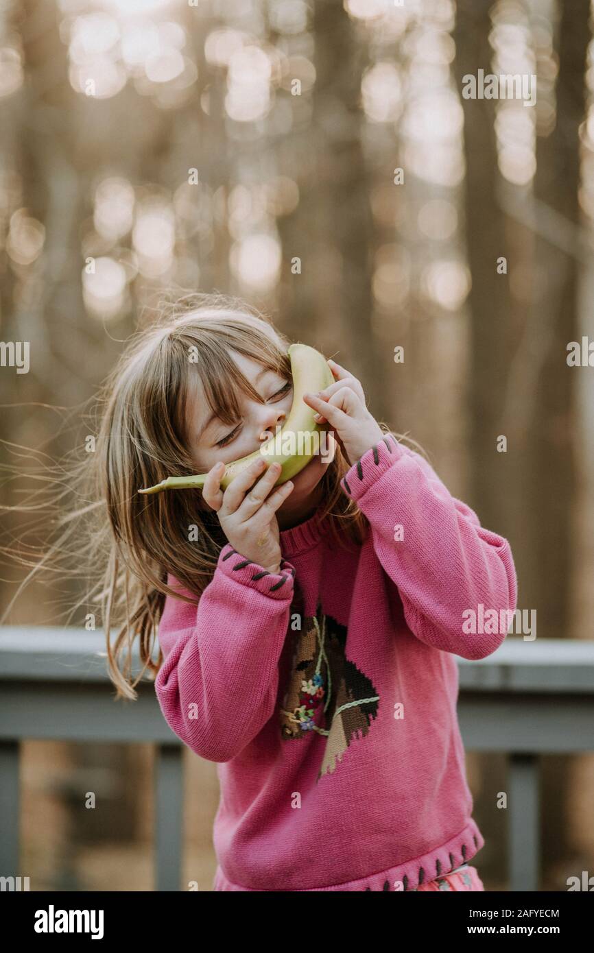 Junges Mädchen mit Banane auf ihrem Gesicht außerhalb lächelnd Stockfoto