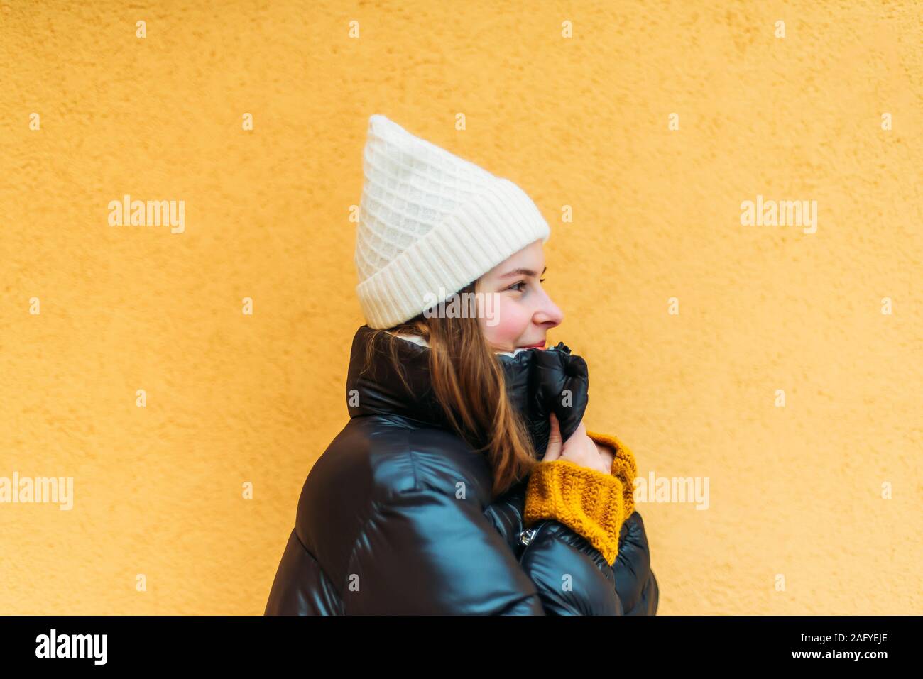 Junge Frau im Stehen gegen die gelbe Wand Stockfoto