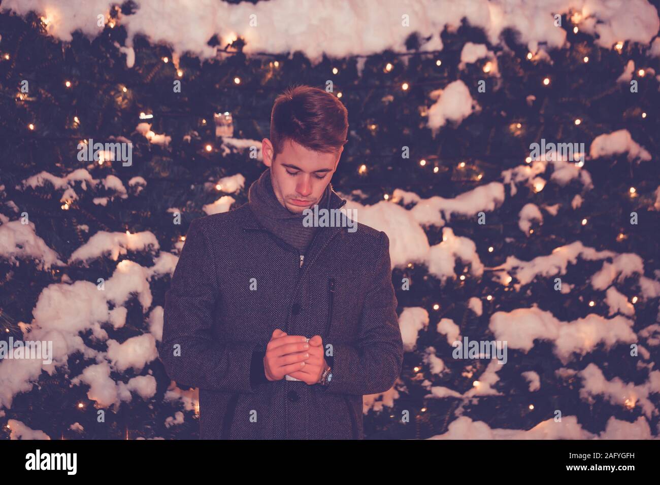 Night scene Portrait des jungen Mannes halten heißes Getränk und winter nacht Lichter im Hintergrund Stockfoto