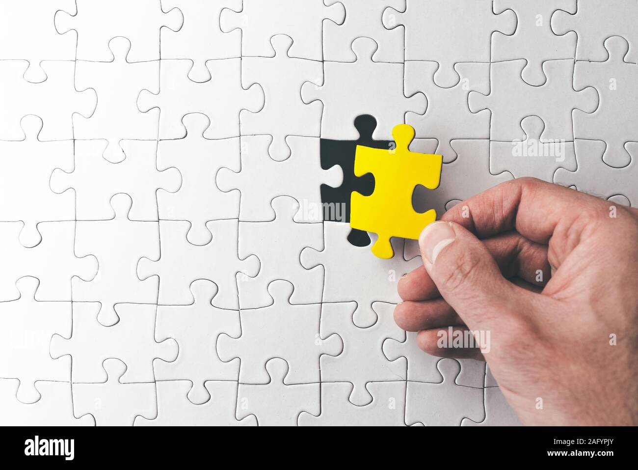 Blick von oben auf die Hand, die letzte passende Puzzleteil kurz vor Fertigstellung Stockfoto