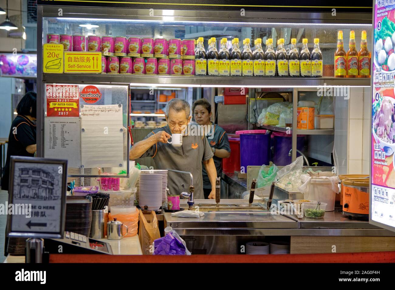 Reifer Mann essen Verkäufer während der Kaffeepause bei Nacht in Singapur Stockfoto