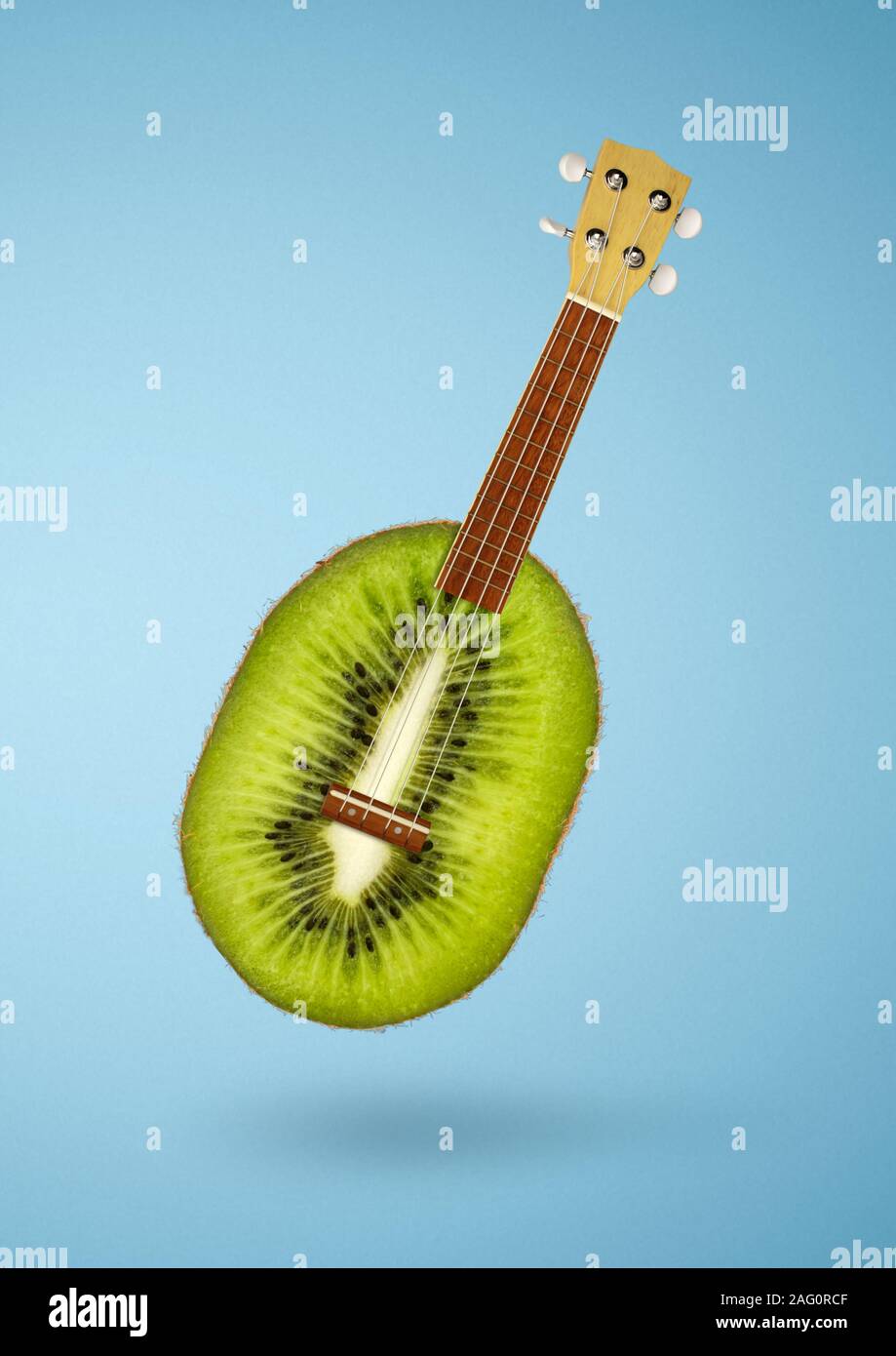 Kreative Küche Konzept, Kiwi als Gitarre auf blauem Hintergrund Stockfoto