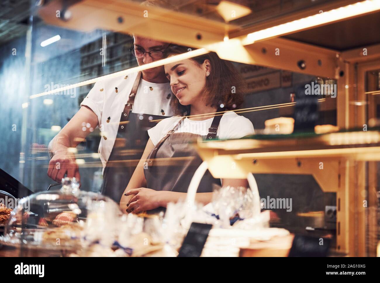 Hinter dem Glas. Helle Streifen. Zwei junge cafe Arbeitnehmer im Innenbereich. Konzeption von Business und Service Stockfoto