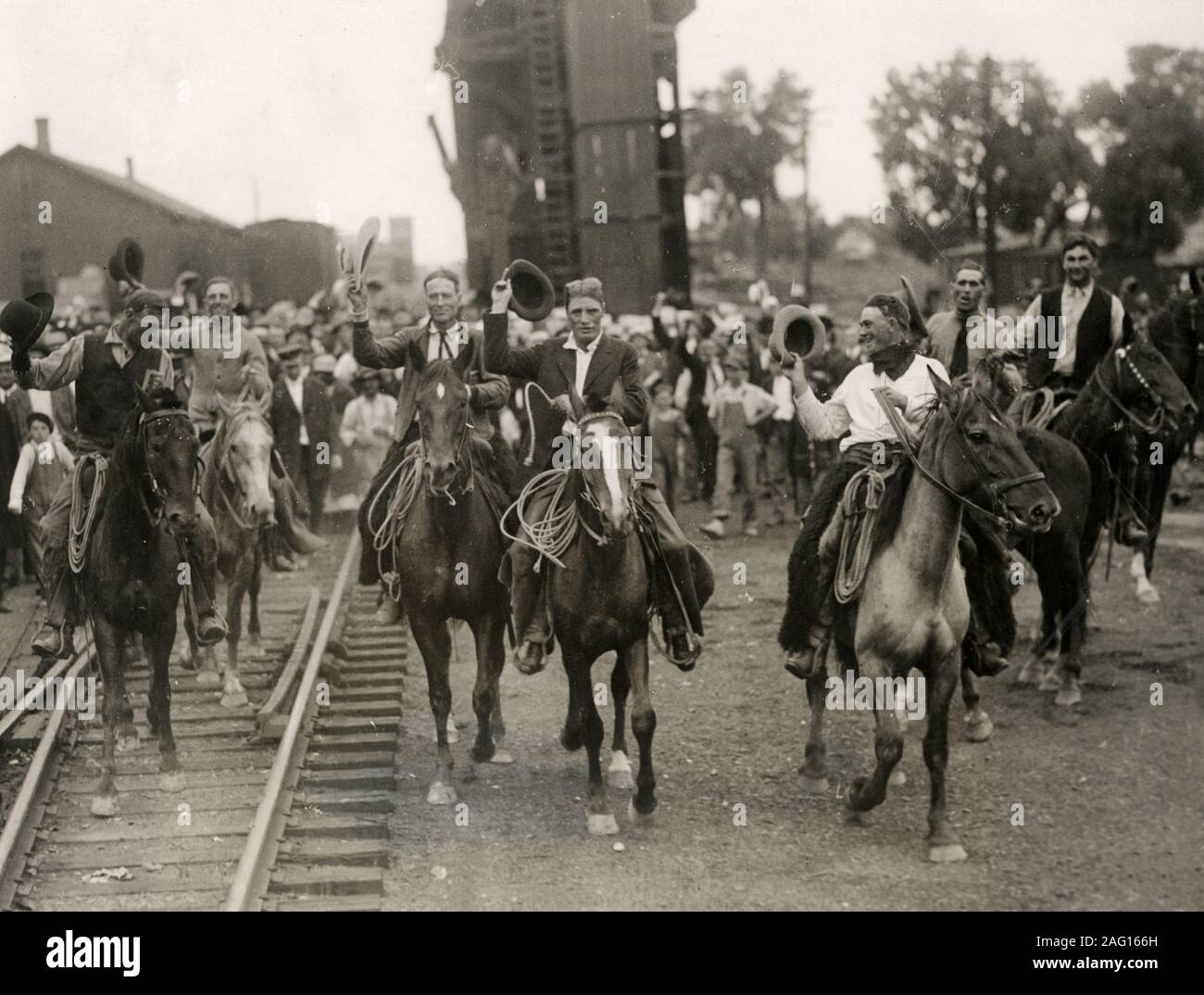 Im frühen 20. Jahrhundert vintage Pressefoto - jubel Cowboys reiten entlang der Bahnstrecke auf Pferden, USA ca. 1920er Jahre. Miles City Montana Stockfoto