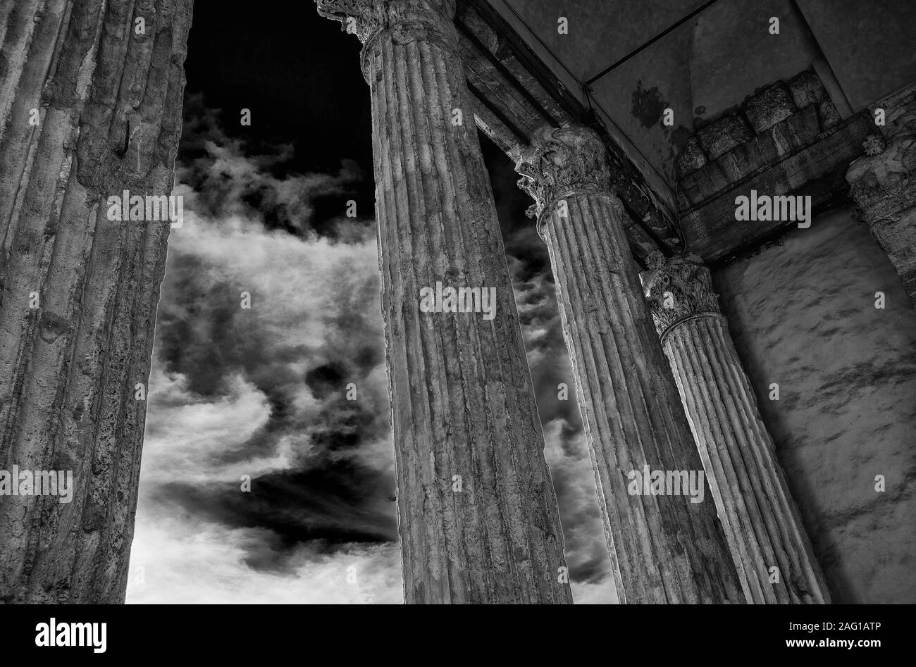 Antike römische Architektur und Archäologie in Assisi. Tempel der Minerva alten Spalten mit Wolken, errichtet im 1. Jahrhundert v. Chr. (Schwarz und Weiß) Stockfoto