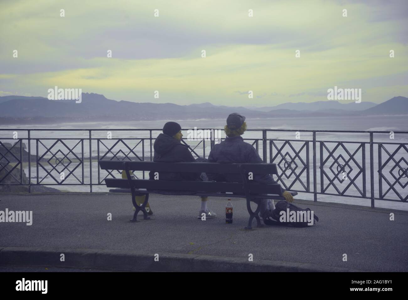 Zwei Männer sitzen auf einer Bank auf dem Meer suchen, pasakdek Stockfoto