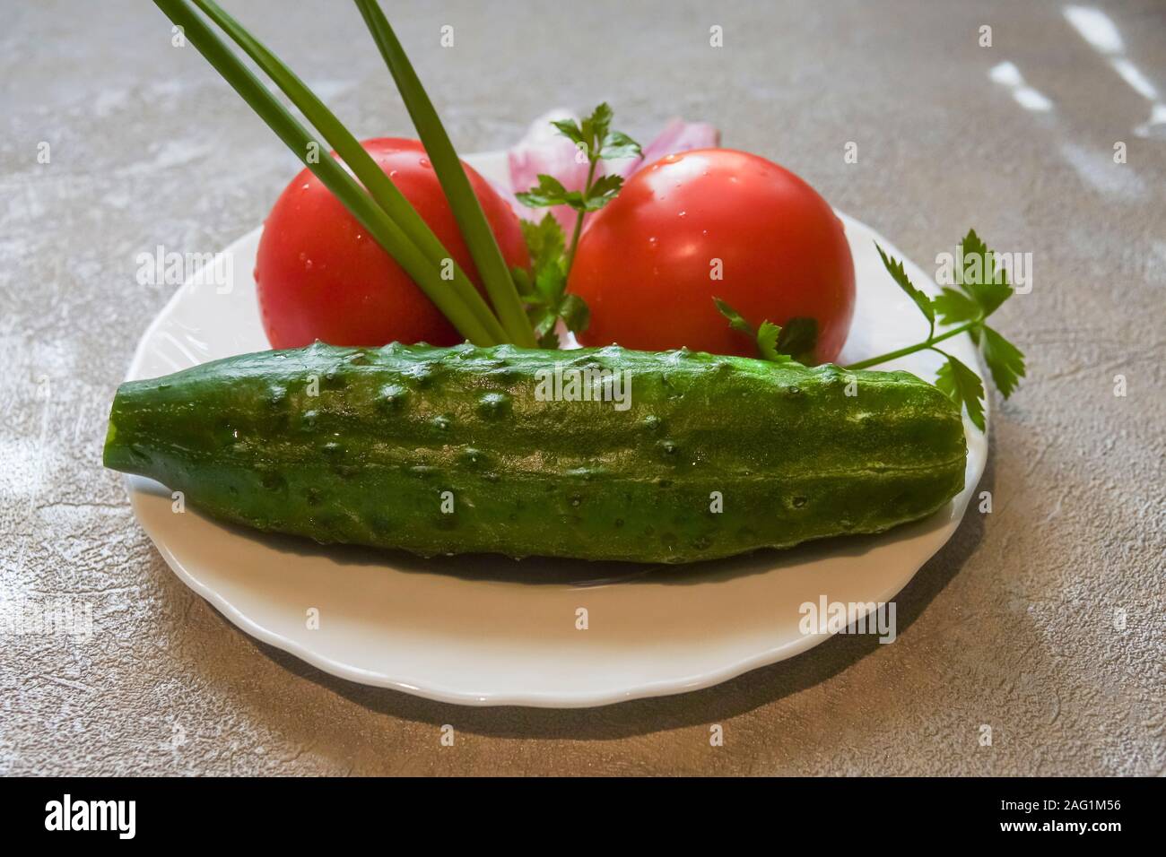 Frisches Gemüse auf einem Teller. Gurke, Tomate und Zwiebel Stockfoto