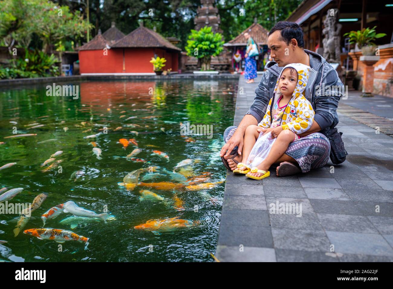 Bali, Indonesien, September 4, 2017: Junge und sein Vater in der Nähe einen Teich mit Koi-Karpfen und Tirta Empul Tempel. An einem bewölkten Nachmittag genommen. Stockfoto