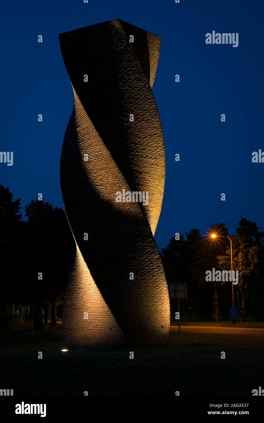 Moderne Architektur bei Nacht in Form einer Helix aus Ziegelsteinen gemauert. Die Wand wird von Lichtstrahlen beleuchtet, wodurch eine malerische strukturierte Wirkung. Stockfoto