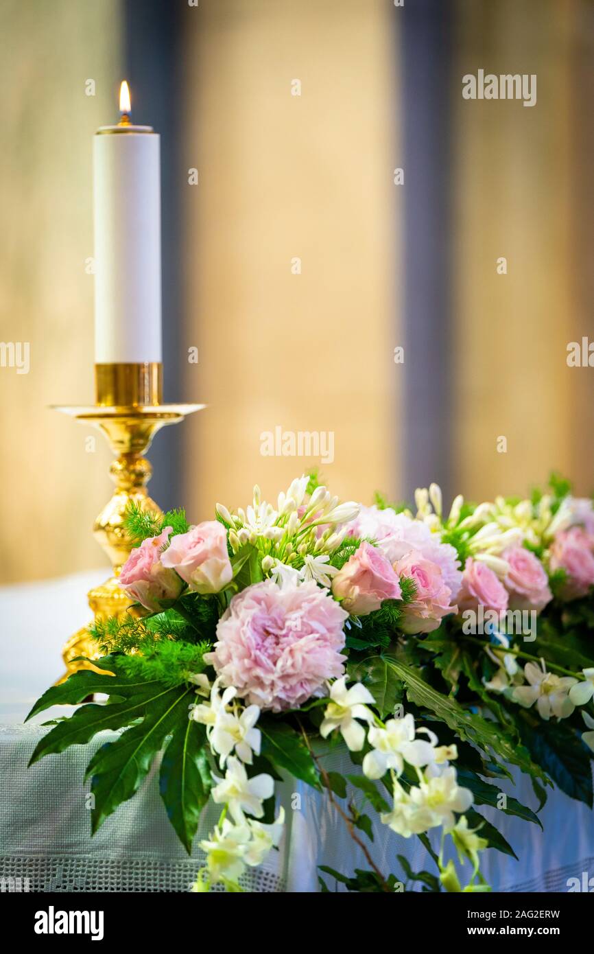 Kerze am Altar mit rosa Blumen Stockfoto