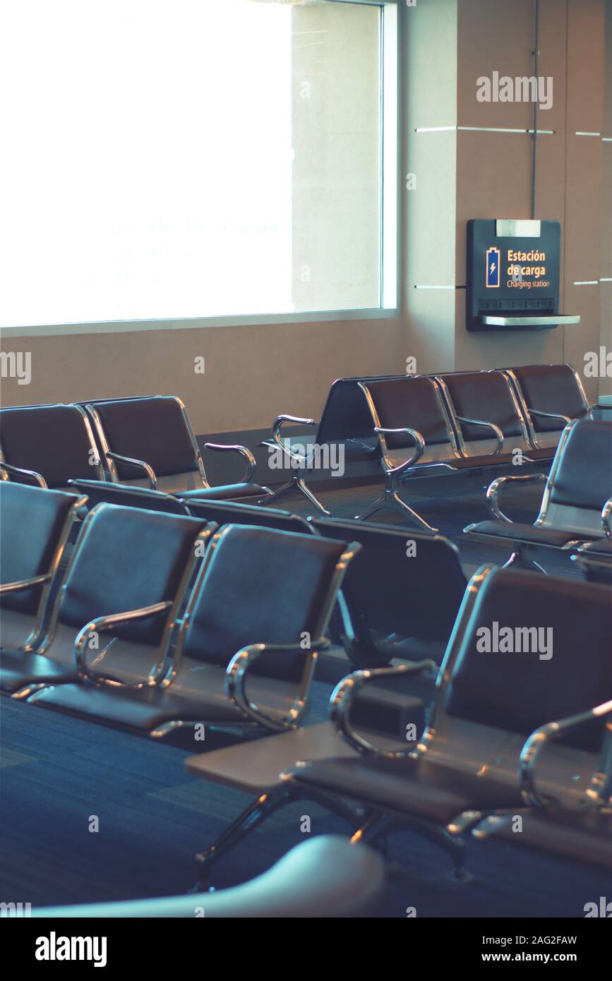 Leere Sitze in der Boarding Area eines Flughafens. Eine Ladestation kann im Hintergrund gesehen werden. Stockfoto