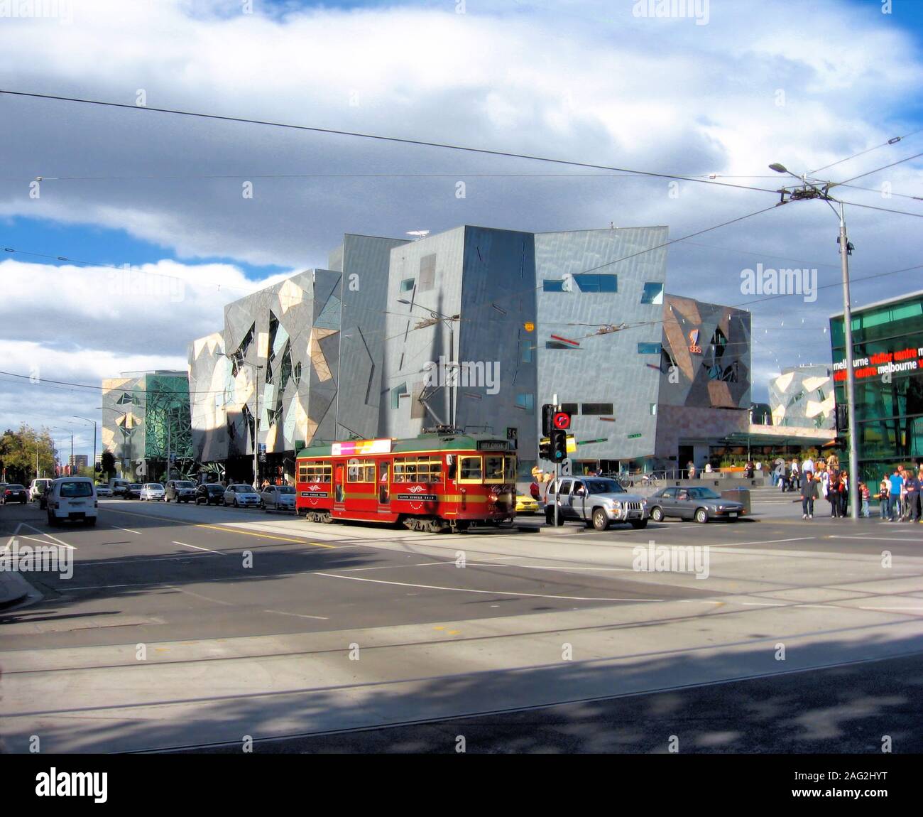 Federation Square und eine rote Straßenbahn in Melbourne, Victoria aus der Ecke Flinders Street und Swanston St. gesehen Stockfoto