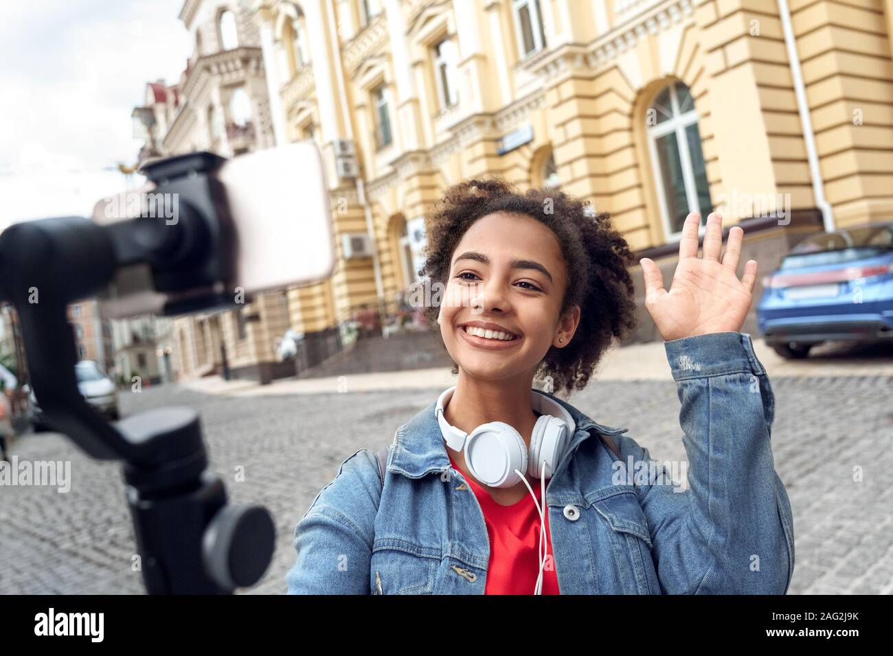 Freizeitaktivitäten im Freien. Junge Mädchen Blogger mit Kopfhörern zu Fuß holding Stabilisator Aufnahme vlog auf dem Smartphone sprechen verspielten close-up Stockfoto