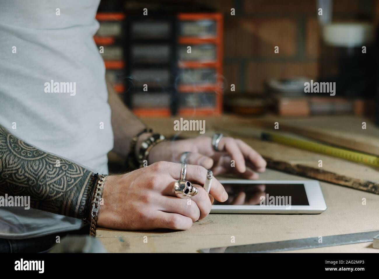 Handwerker Künstler in einer Tablette und einige Ideen für einen neuen Designer Holz- Produkt aus seinem Hause Werkstatt beim Rauchen einer Zigarette Stockfoto