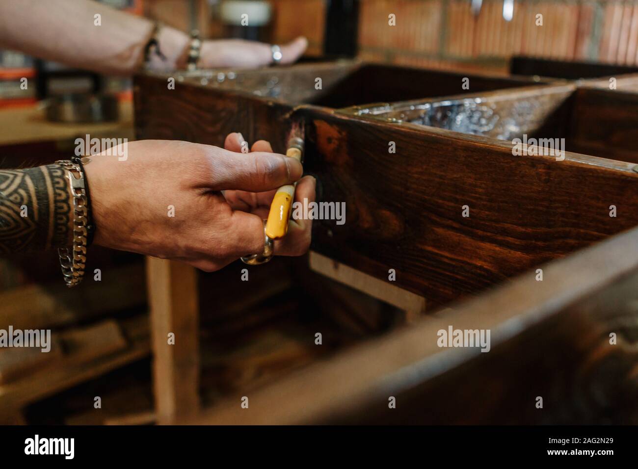 Die Hände eines Zimmermanns Bürsten eine hölzerne Möbel Handwerk workshop Stockfoto