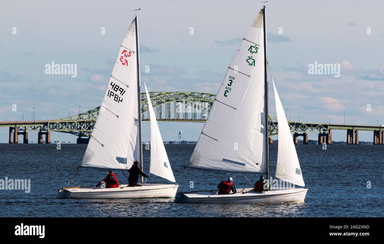 Babylon, New York, USA - 7. Dezember 2019: Nahaufnahme von zwei Person saiboats Segeln in einem Dezember Regatta in der Great South Bay mit der Brücke in Stockfoto