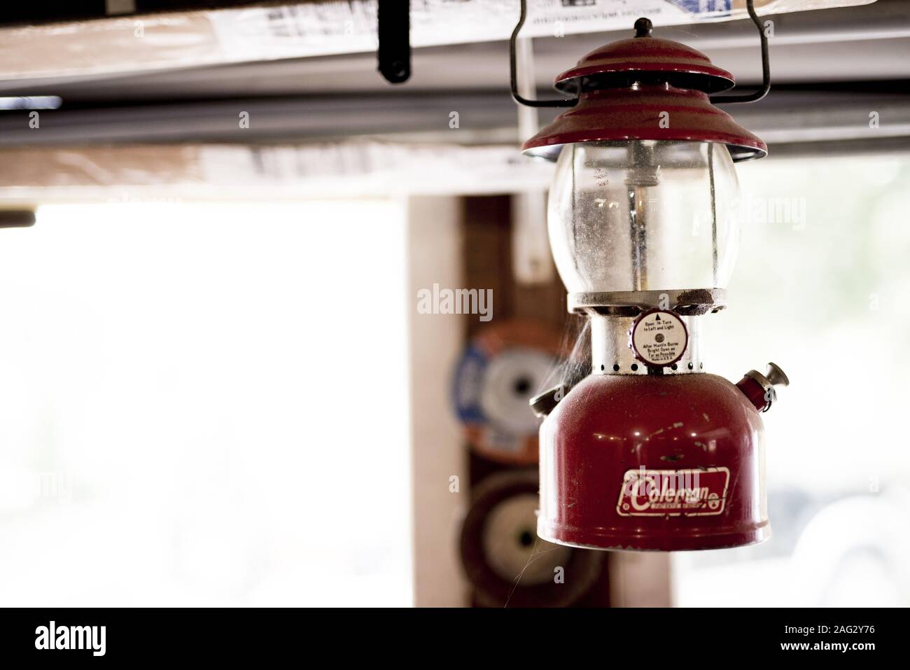 JACKSON, VEREINIGTE STAATEN - Jan 01, 2019: Alte Colman Lampe hängen in eine Garage. Das Fenster wird gesehen hinter ein wenig verschwommen. Stockfoto