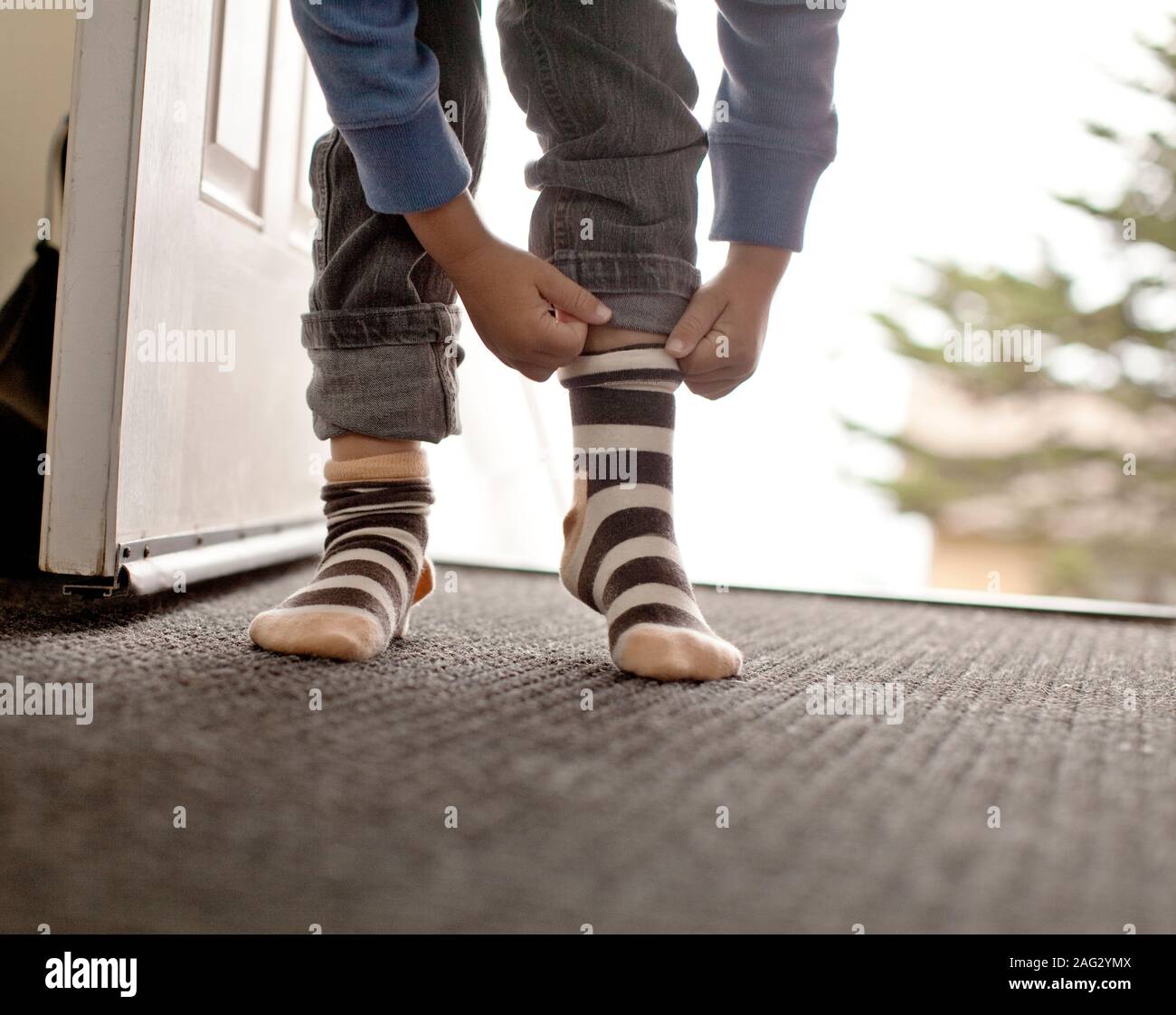 Junge rollt Jeans in der Tür. Stockfoto