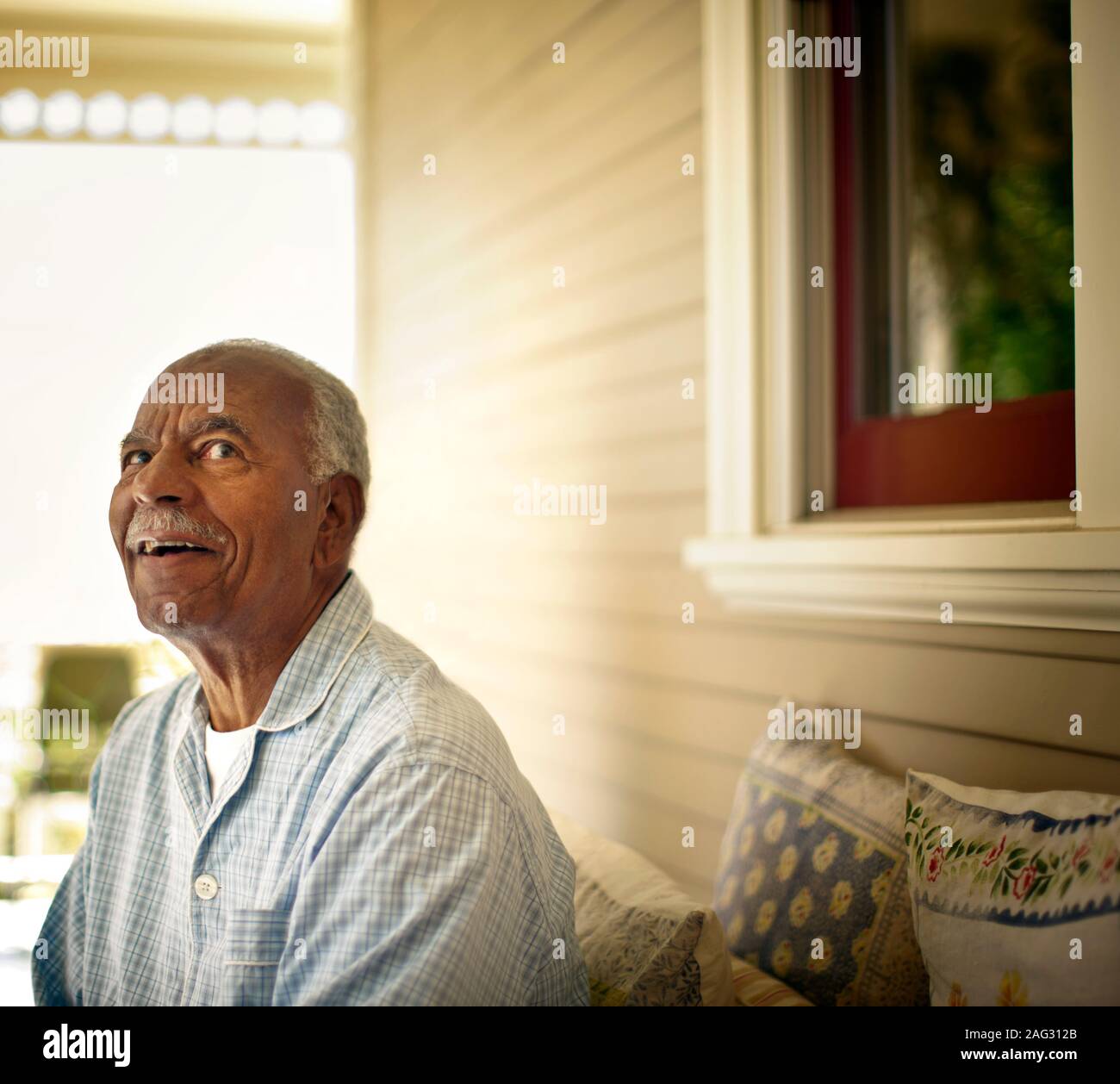 Lächelnd älterer Mann sitzt auf der Terrasse des Rest-home. Stockfoto